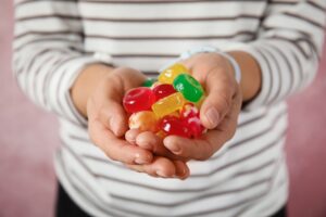 Woman,Holding,Many,Colorful,Candies,On,Color,Background,,Closeup